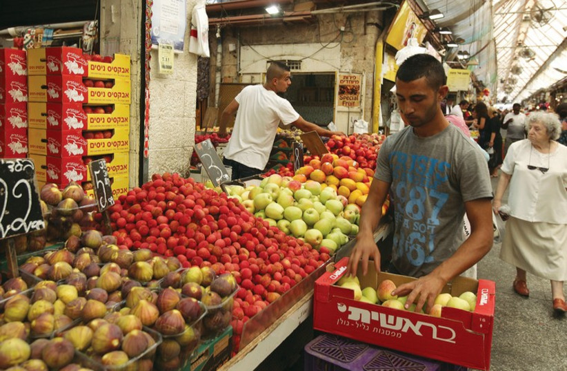 A vegetable vendor restocks his supply in Jerusalem’s Mahaneh Yehuda market. (photo credit: MARC ISRAEL SELLEM/THE JERUSALEM POST)