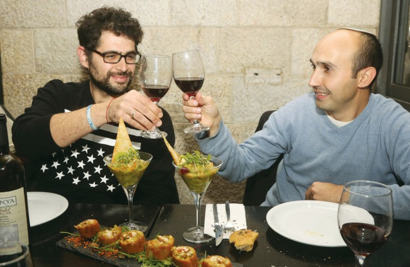 IDF veterans  and musicians Shai Ben-Shushan and Shlomo Gvili toast with a glass of wine at La Boca restaurant in Jerusalem (photo credit: MARC ISRAEL SELLEM)