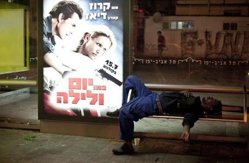 An African migrant worker sleeps on a bench of a bus station in south Tel Aviv (photo credit: REUTERS)