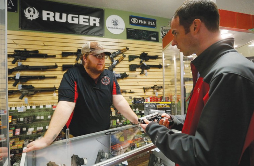 AN EMPLOYEE speaks to a customer about the purchase of a handgun at a store in Bridgeton, Missouri, last month. (photo credit: REUTERS)