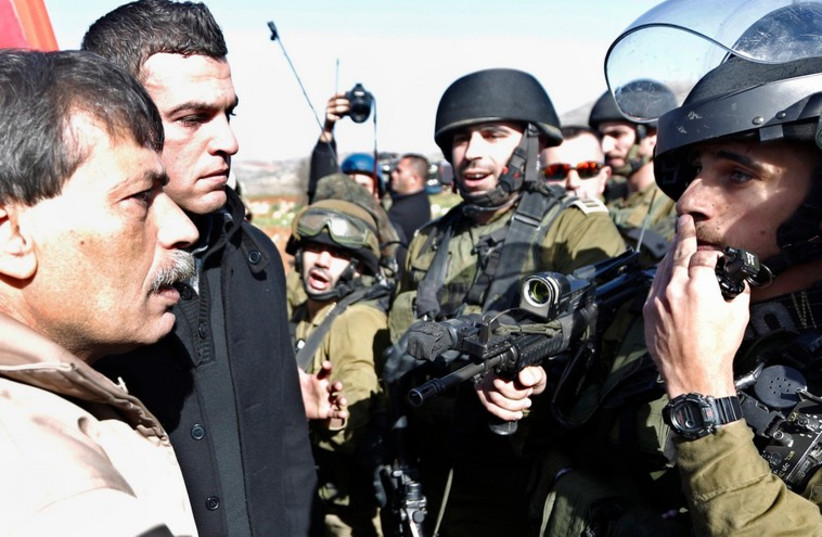 PA Minister Ziad Abu Ein faces off with IDF soldier during protest in West Bank, December 10 (photo credit: REUTERS)