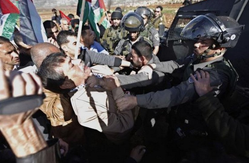 Palestinian minister Ziad Abu Ein (L) scuffles with an Israeli border policeman near the West Bank city of Ramallah December 10, 2014.  (photo credit: REUTERS)