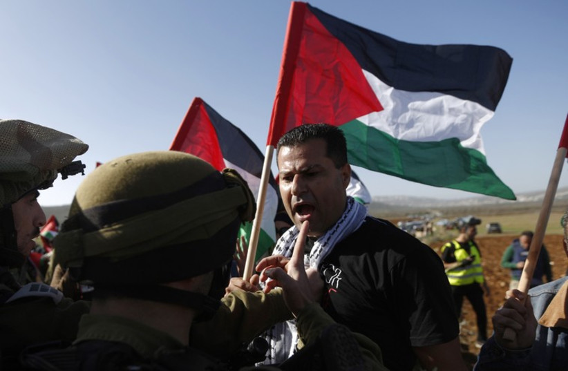 A Palestinian argues with IDF soldiers near Ramallah, December 10, 2014. (photo credit: REUTERS)