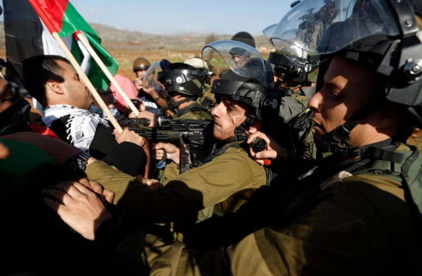 Israeli soldiers scuffle with Palestinians during a protest against Jewish settlements near the West Bank city of Ramallah December 10 (photo credit: REUTERS)