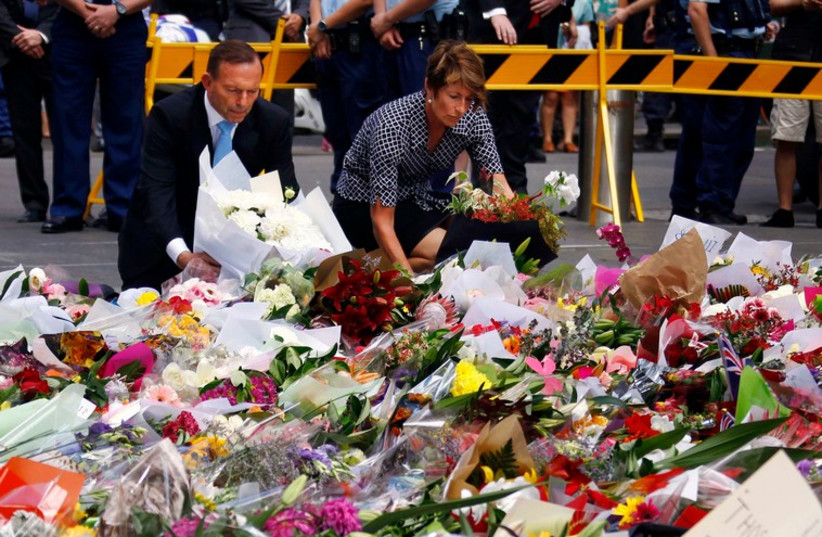 Australian Prime Minister Tony Abbott and his wife Margie place flowers at the makeshift memorial for the hostage victims of the Sydney cafe siege (photo credit: REUTERS)