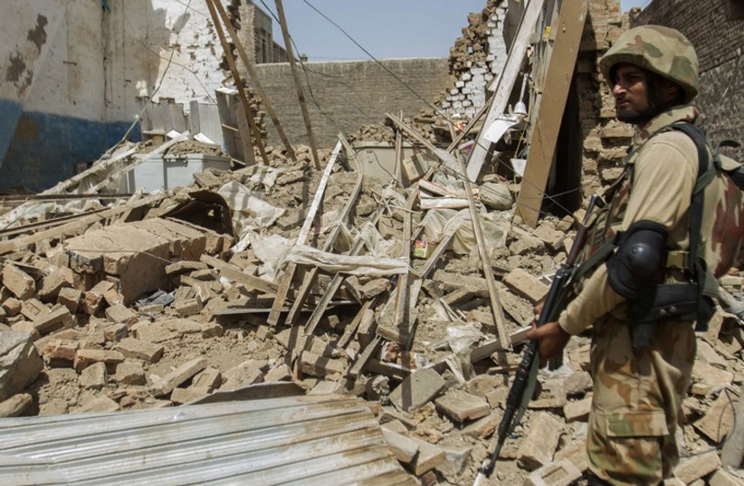 A Pakistani soldier standing near the debris of a house which was destroyed during a military operation against Taliban militants. (photo credit: REUTERS)