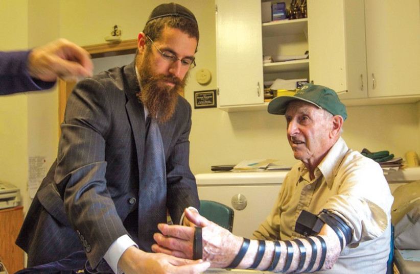 RABBI ABRAHAM SIMMONDS helps Harvey Kleiman put on tefillin at the Hirsch Farm in Saskatchewan in October. (photo credit: YOSSI ALONI)