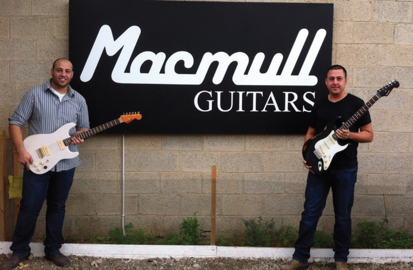 Tal (left) and Shai Macmull showcase their guitars outside the workshop (photo credit: NAAMA BARAK,MUSÉE DE LA TOUR DE DAVID,MYISRAEL)
