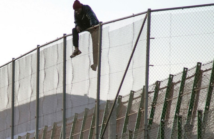 A MAN sits on a fence in Melilla, a Spanish enclave in North Africa. Those successfully scaling the fence are entitled to apply for asylum. (photo credit: REUTERS)