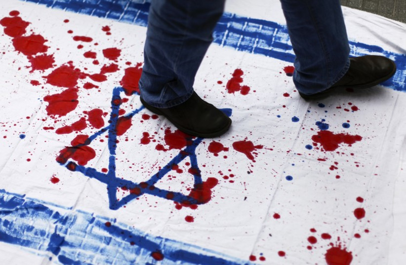 A Venezuelan student walks over a cloth with red paint and the Star of David during an anti-Israel demonstration in Caracas. (photo credit: REUTERS)