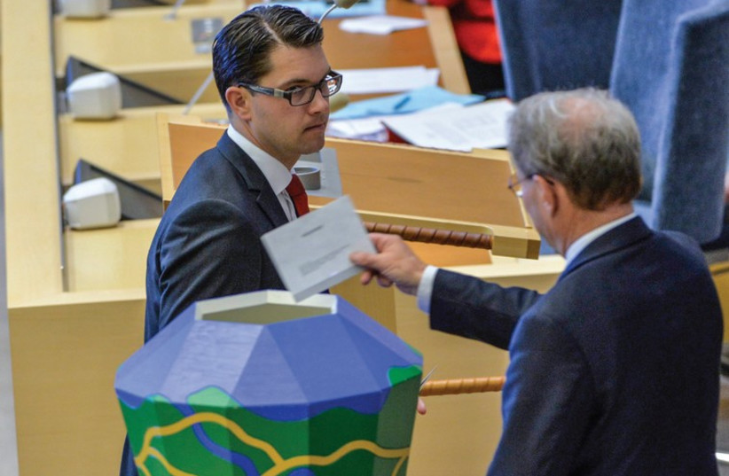 The leader of the Sweden Democrats Jimmie Akesson hands over his ballot to parliament speaker Per Westerberg during voting for the second deputy speaker in the Swedish parliament, in Stockholm in September. (photo credit: REUTERS)