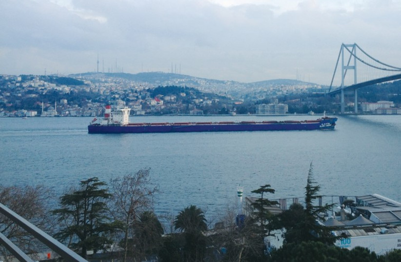 An international cargo ship passes under the First Bosporus Bridge (photo credit: SETH J. FRANTZMAN)