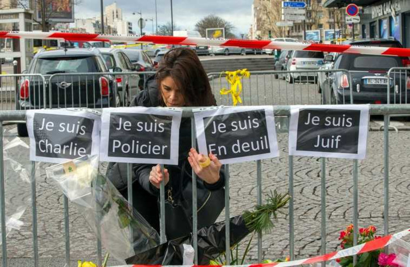 A woman hangs signs reading (from L to R) "I am Charlie", "I am police officer", "I am mourning" and "I am Jewish" while paying tribute to victims of a kosher deli siege in Paris (photo credit: REUTERS)