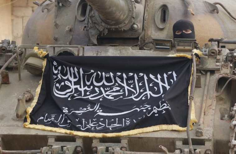 A member of al-Qaida's Nusra Front sits in a tank decorated with the Nusra flag near al-Zahra village, north of Aleppo (photo credit: REUTERS)