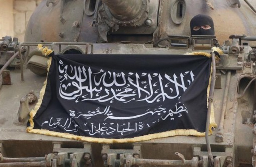 A member of al-Qaida's Nusra Front sits in a tank decorated with the Nusra flag near al-Zahra village, north of Aleppo (photo credit: REUTERS)