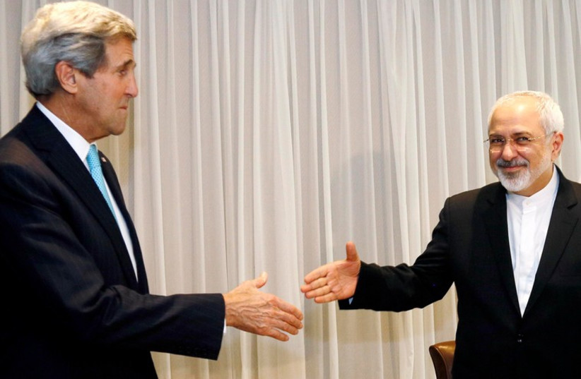 US Secretary of State John Kerry shakes hands with Iranian Foreign Minister Mohammad Javad Zarif before a meeting in Geneva January 14, 2015 (photo credit: REUTERS)
