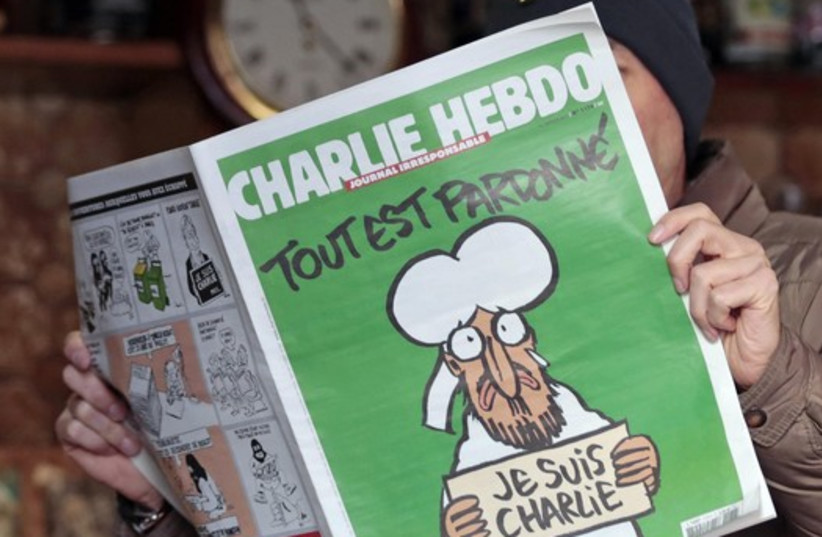 A man poses with the new issue of French satirical weekly Charlie Hebdo at a cafe in Nice. (photo credit: REUTERS)
