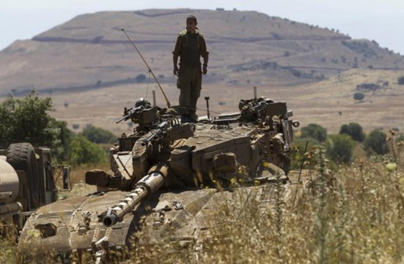 An IDF soldier stands atop a tank near Alonei Habashan on the Golan Heights, close to the ceasefire line between Israel and Syria (photo credit: REUTERS)