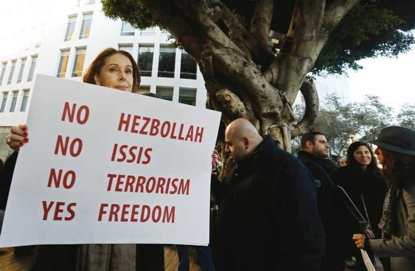A woman holds a sign in Beirut in a solidarity protest for the victims of the Paris terrorist attacks. (photo credit: REUTERS)
