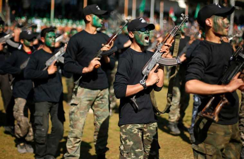 Palestinian youths hold weapons during a military-style graduation ceremony.  (photo credit: REUTERS)
