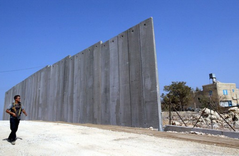 An Israeli security man patrols a part of the separation fence near the Jewish settlement of Elkana (photo credit: REUTERS)