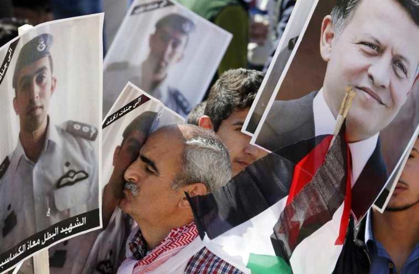 A Jordanian protester kisses a poster bearing the image of Jordanian pilot Muath al-Kasaesbeh during a rally to show their loyalty to King Abdullah (photo credit: REUTERS)