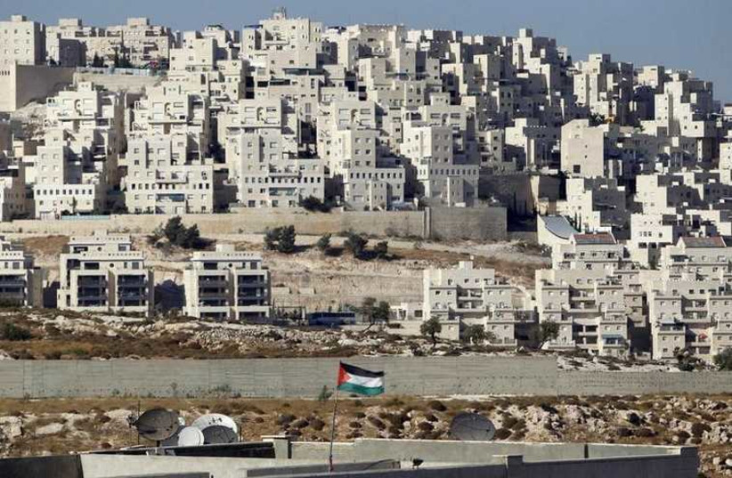 A Palestinian flag flutters in front of the Jerusalem neighborhood of Har Homa (photo credit: REUTERS)