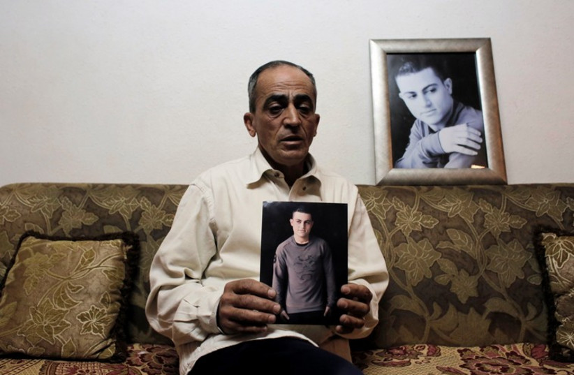 Said Musallam, an Israeli Arab whose son, Muhammad, is being held by Islamic State in Syria as an alleged spy, holds his photograph in his east Jerusalem home  (photo credit: REUTERS)