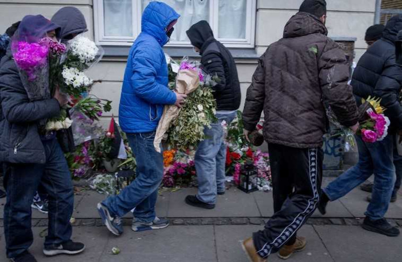 People who knew the gunman remove flowers laid at the place where he was killed by police. (photo credit: REUTERS)