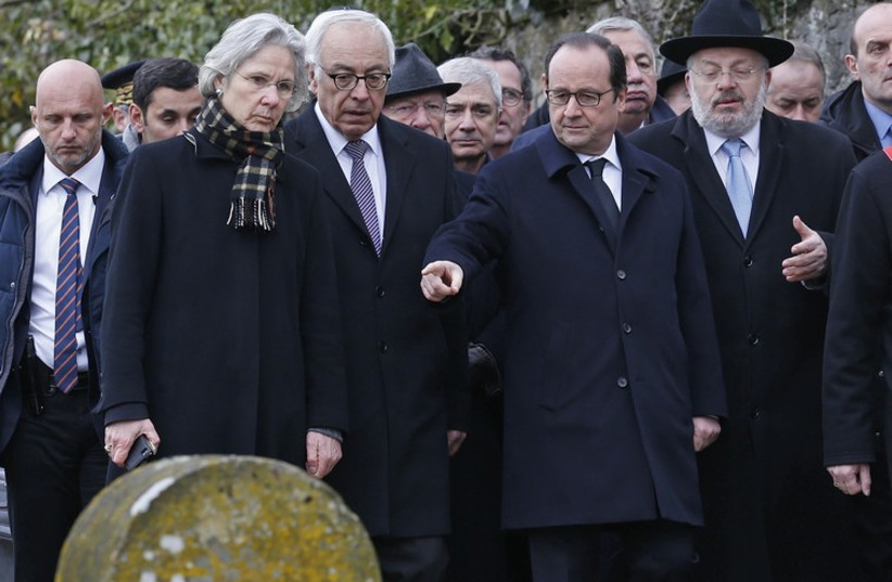 French President Francois Hollande (2ndR), Israeli ambassador to France Yossi Gal (C), and Strasbourg and Bas-Rhin Grand Rabbi Rene Gutman (R) walk past desecrated tombstones during a visit at the Sarre-Union Jewish cemetery, eastern France, February 17, 2015. (photo credit: REUTERS)
