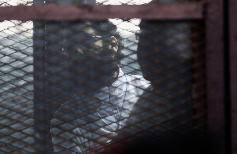 Activist Alaa Abdel Fattah stands behind bars before his verdict is announced at a court in Cairo, February 23, 2015. (photo credit: REUTERS)