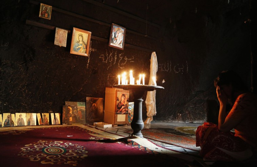A woman prays inside a damaged church in Maaloula, Syria (file). (photo credit: REUTERS)