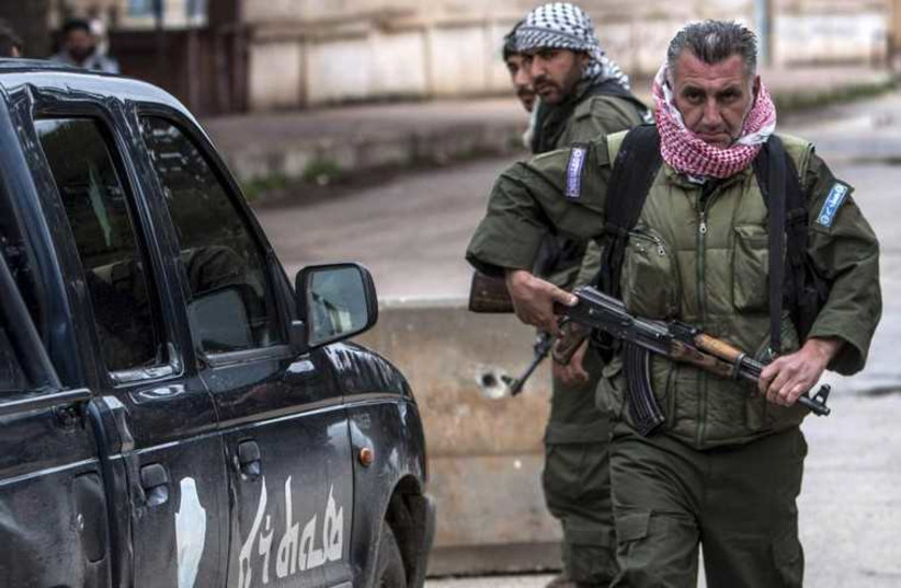 Christian fighters of Sutoro (The Syriac Security Office) carry their weapons as they man a checkpoint in the town of Tel Tamr February 25, 2015.  (photo credit: REUTERS)