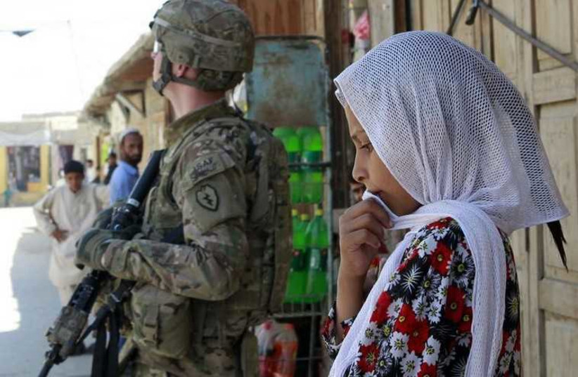 A girl stands next to a US in Jalalabad, Afghanistan (photo credit: REUTERS)