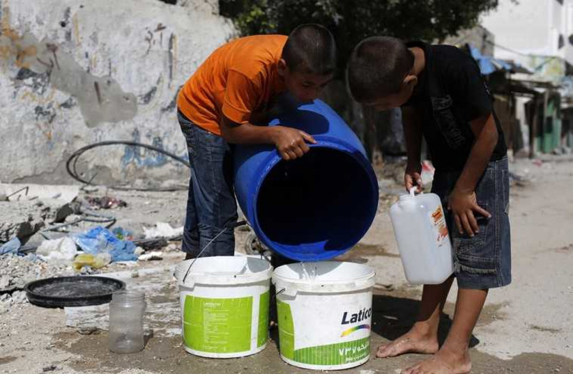 Palestinian children in Gaza fetch water from a container (photo credit: REUTERS)