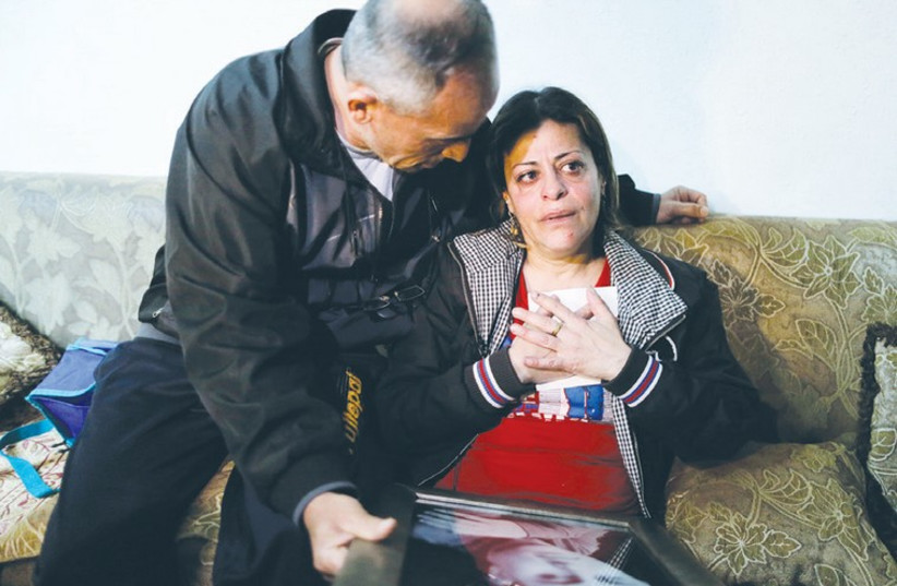 THE PARENTS of Israeli teen Muhammad Said Musallam, whom a child purportedly shot dead in an Islamic State video, react on Tuesday as they hold pictures of him in their Jerusalem home. (photo credit: REUTERS)