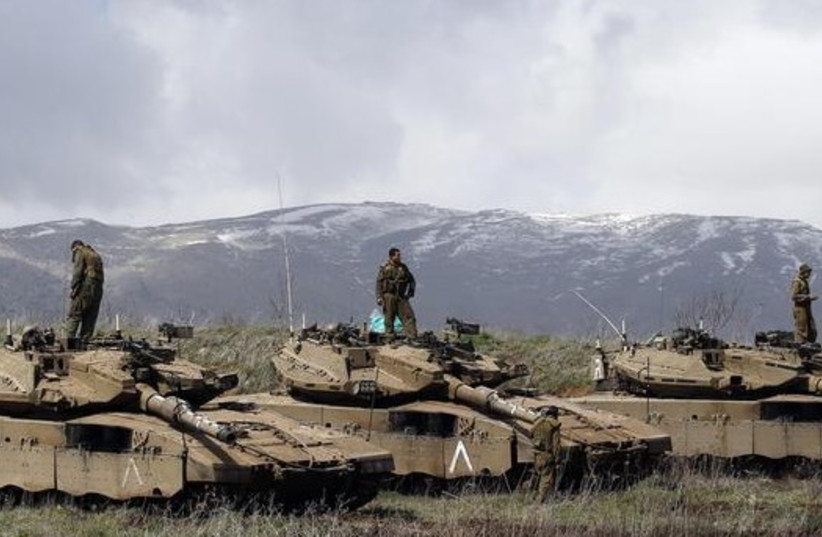 Israeli soldiers stand atop tanks in the Golan Heights near Israel's border with Syria (photo credit: REUTERS)