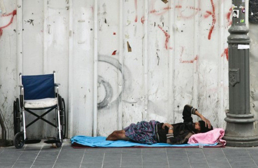 A homeless man lies on the street. (photo credit: MARC ISRAEL SELLEM/THE JERUSALEM POST)