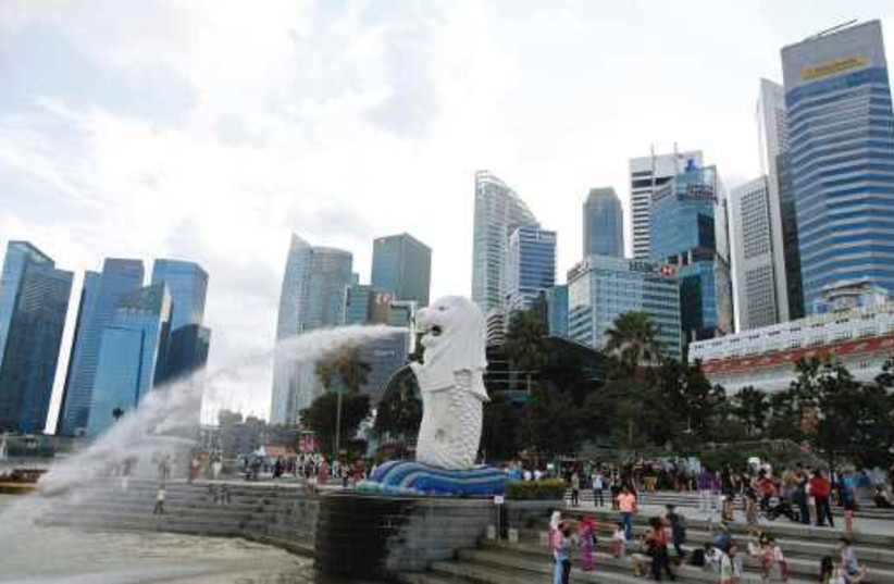 TOURISTS TAKE pictures next to the Merlion statue in the central business district of Singapore, last month. (photo credit: REUTERS)