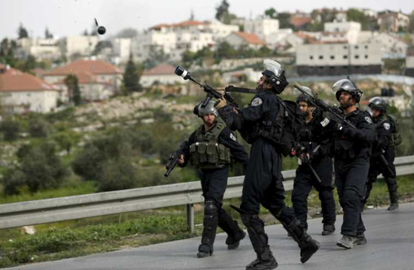 An Israeli border policeman fires a tear gas canister towards Palestinian stone-throwers (photo credit: REUTERS)