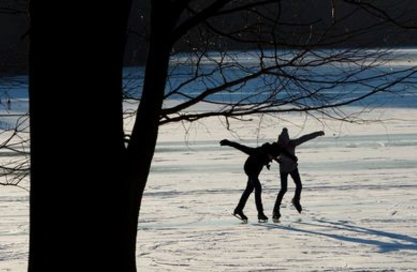 A woman and a girl skate on a frozen lake in Berlin