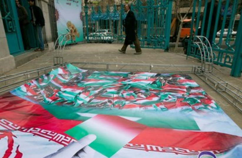 Iranian man walks past election banner