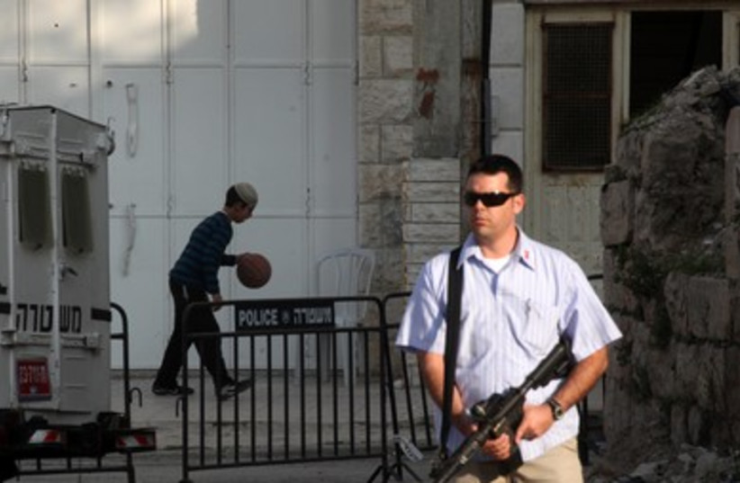 Armed guard stands by while settler plays ball