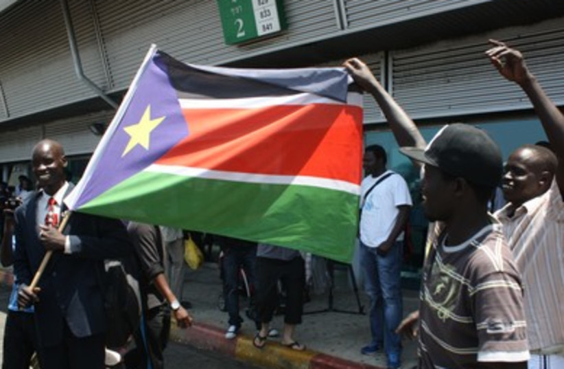 Migrants dance with flag of South Sudan