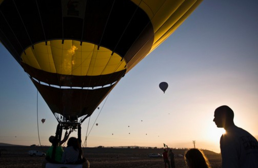 People sit in the basket of a hot air balloon as it takes fl