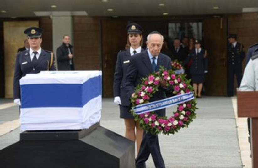 President Shimon Peres lays a wreath on the coffin of former primer minister Ariel Sharon.