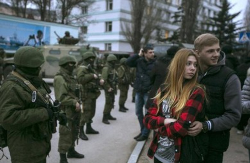A Ukrainian couple stands next to Russian soldiers in the Crimean town of Balaclava.