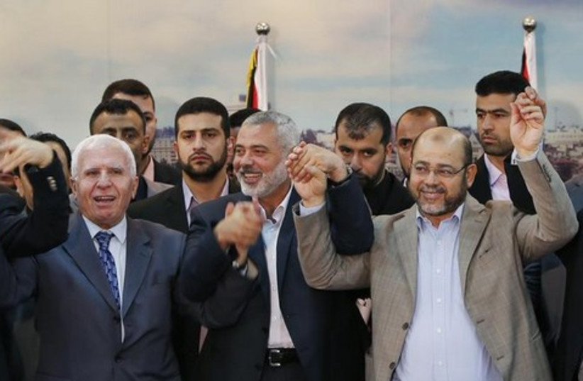 Senior Fatah official Azzam Al-Ahmed (L), head of the Hamas government Ismail Haniyeh (C) and senior Hamas leader Moussa Abu Marzouq hold their hands after announcing a reconciliation agreement in Gaza City April 23, 2014.  (credit: REUTERS)