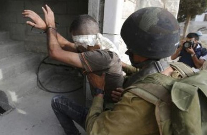 An IDF soldier detains a Palestinian during an operation to locate three Israeli teens near Hebron.