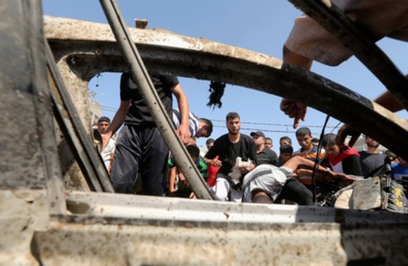 Palestinians survey the wreckage of an IAF strike that killed two terrorists in Gaza.